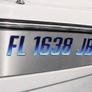 Close-up of a boat registration number plate with 'FL 1638 JB' on a metallic background.