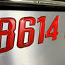Domed red boat registration numbers affixed to a boat hull.