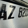 Metallic license plate with 'AZ 8205' text on a reflective surface