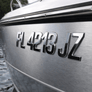 Close-up of a boat's nameplate with registration number on a water background