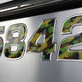 The image shows a close-up of a boat's registration number, '558442', with camouflage-style raised domed lettering in chrome.
