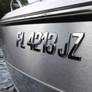 Close-up of a boat's nameplate with registration number on a water background